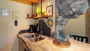 Une cuisine dotée d’un comptoir en granit, d’un évier en acier inoxydable et d’un mur décoratif en pierre.