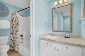 Un bagno con doccia, WC, lavandino e mobile contenitore con cassetti.