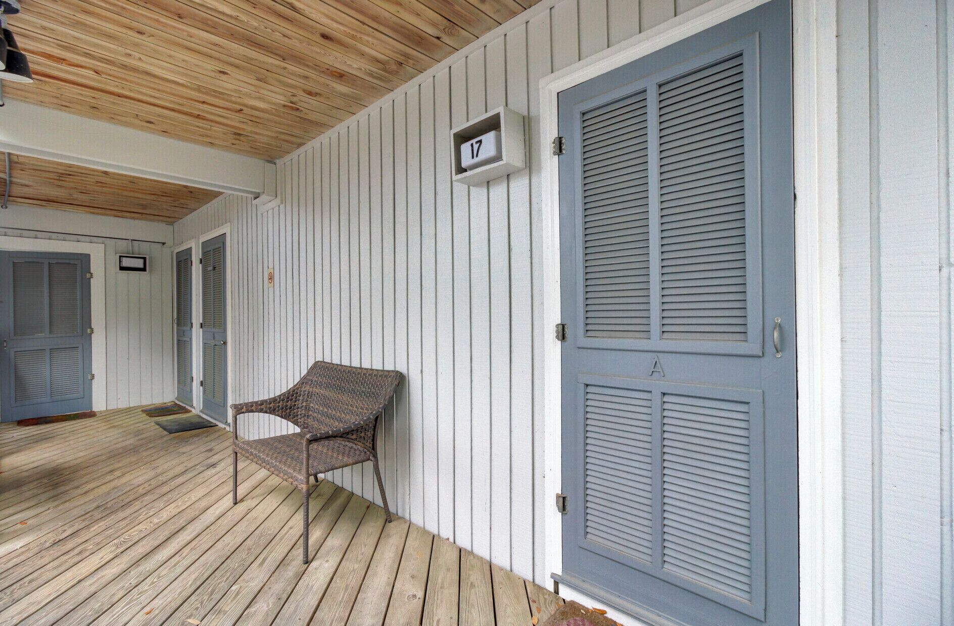 A covered porch with a wicker chair, a door with shutters, and a mailbox with the number 17.