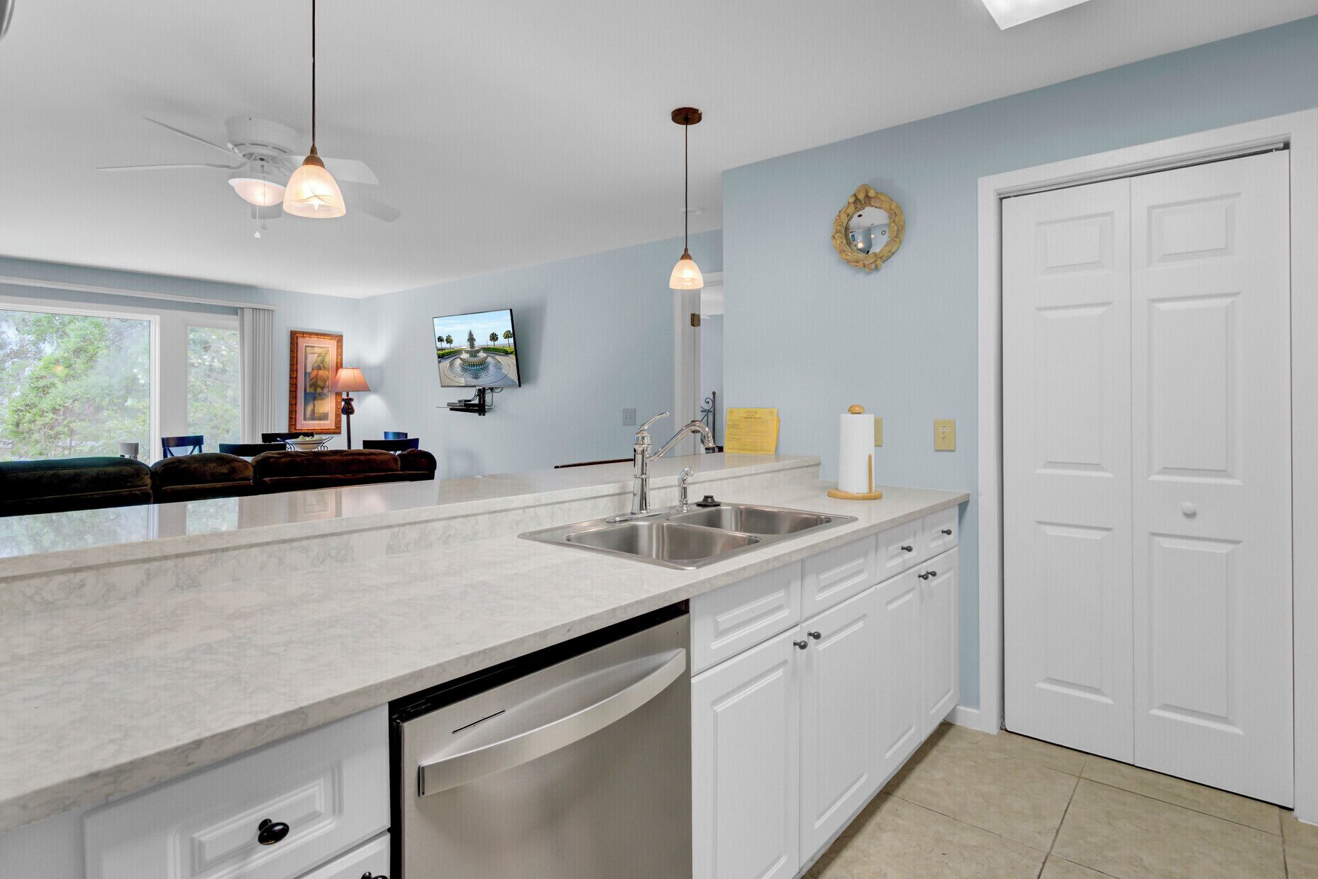 A modern kitchen with a large island, white cabinetry, and a built-in dishwasher.