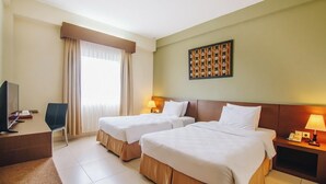 Camera d'albergo con due letti, una scrivania, una sedia, una televisione e un quadro appeso al muro.