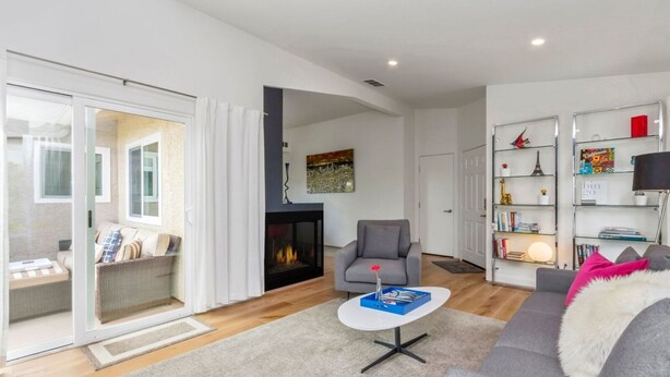A modern living room with a fireplace, a grey sofa, a white coffee table, and a bookshelf. - ★Modern Ritz Pointe Beach Escape★ STR 23-0009 (Dana Point)