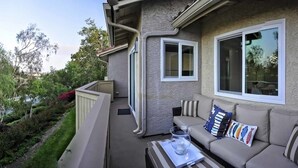 A balcony with a beige sofa, two windows, and a small table with a glass. - ★Modern Ritz Pointe Beach Escape★ STR 23-0009 (Dana Point)