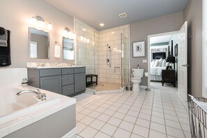 Ein modernes Badezimmer mit einer großzügigen Badewanne, einer bodenebenen Dusche und einem WC.