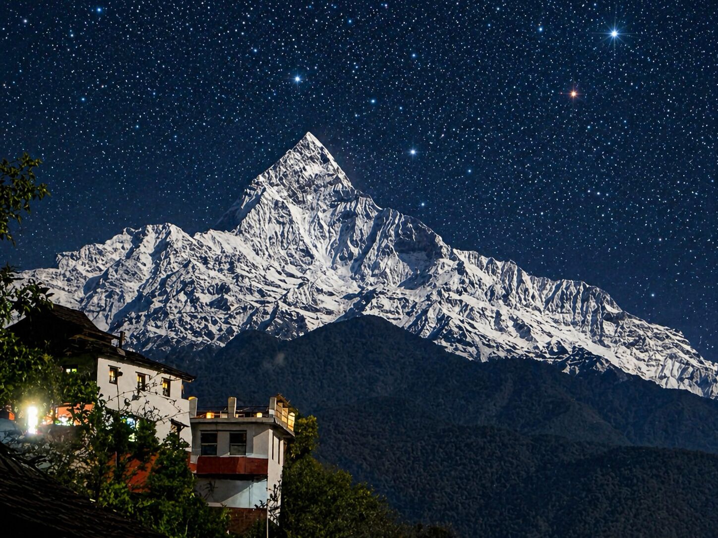 A snow-covered mountain under a starry night sky.