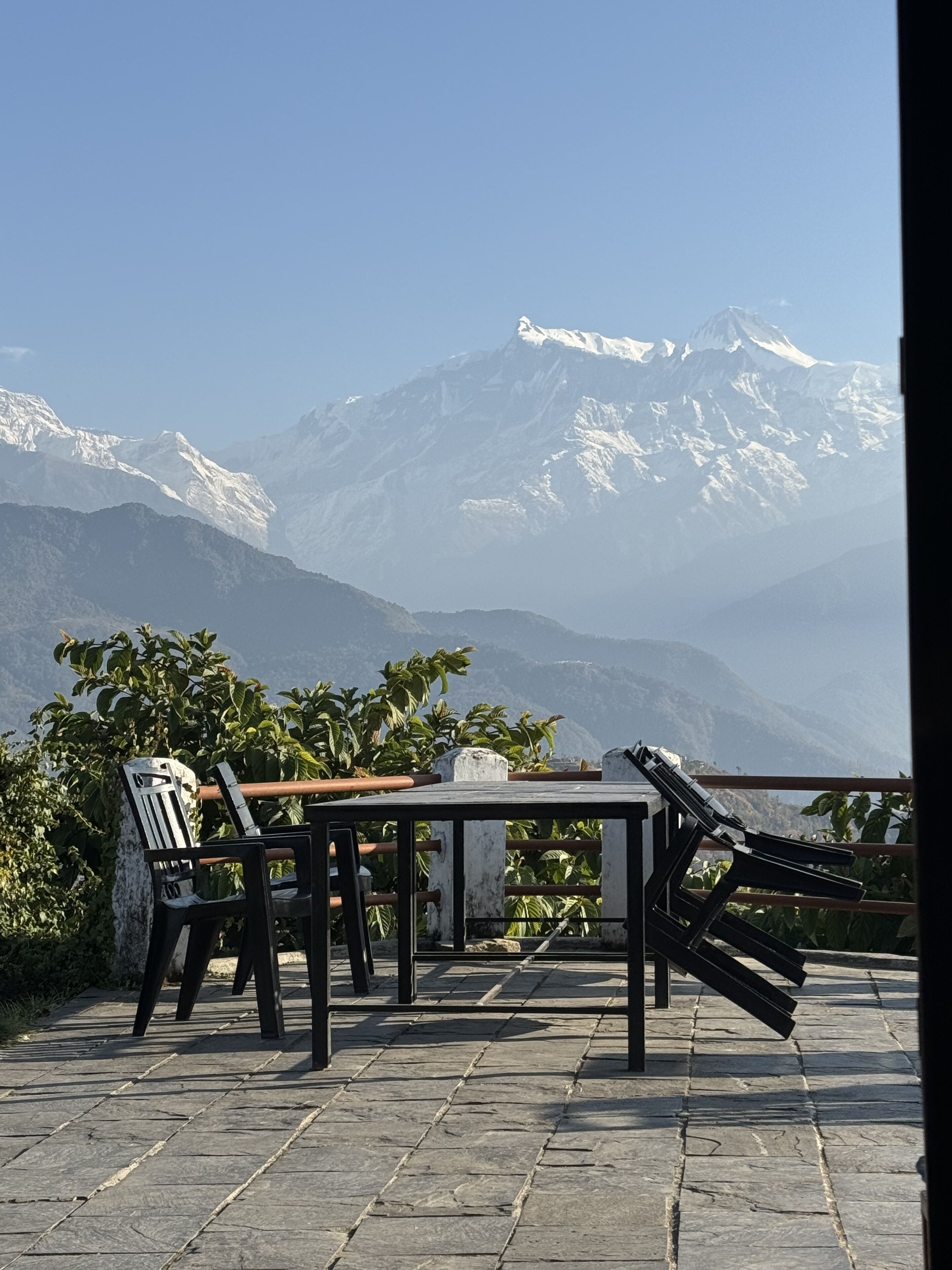 Una terraza con una mesa y sillas con vistas a una cadena montañosa.