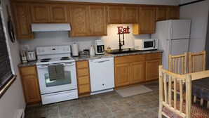 A kitchen with wooden cabinets, a white stove, a dishwasher, a microwave, and a refrigerator. - Experience Unparalleled Luxury and Convenience at Our Exquisite Condo (West Yellowstone)