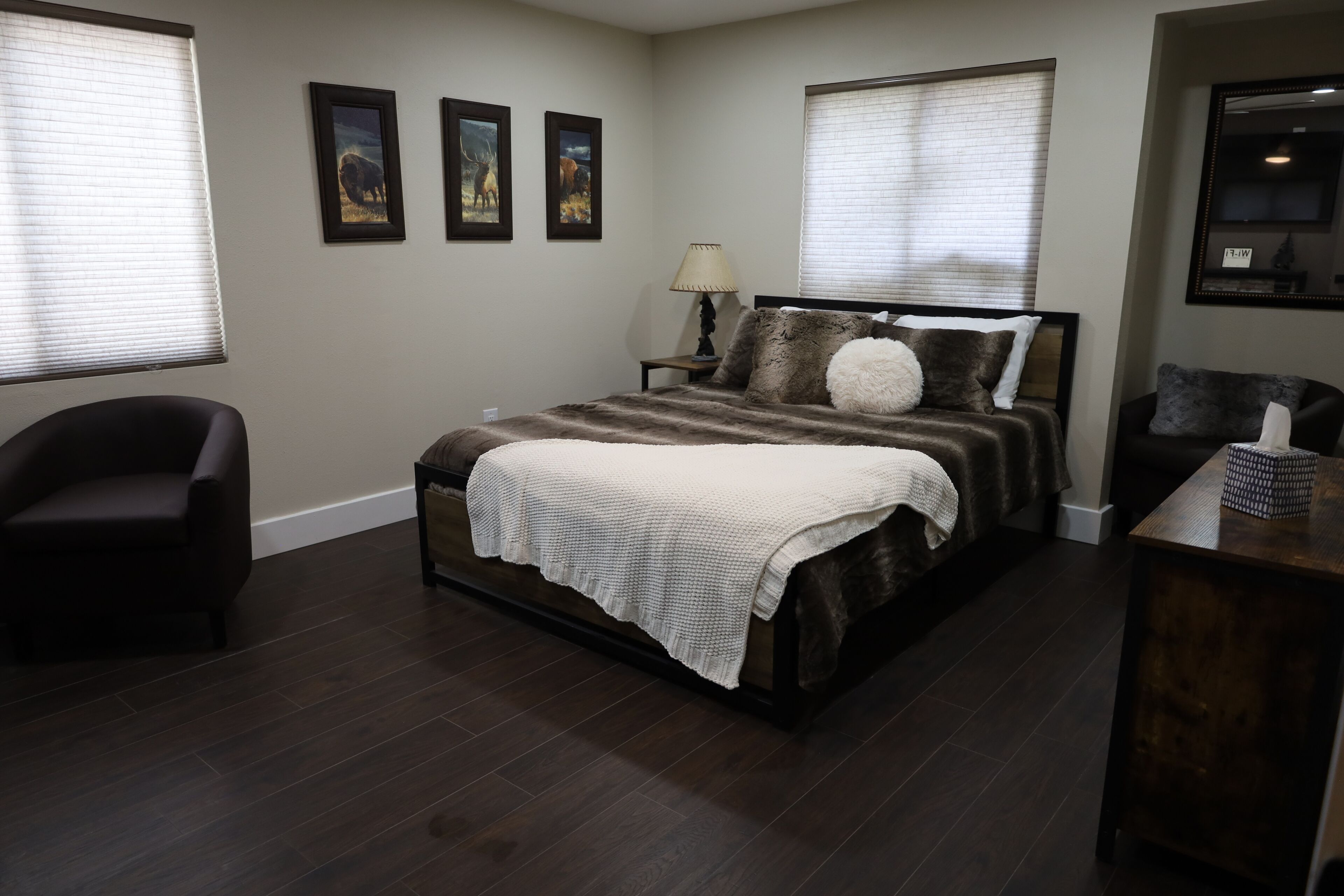 A bedroom with a large bed, a chair, a nightstand, and a dresser.