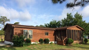 A wooden cabin with a covered porch and a small deck. - The West Bay Lodge offers spacious amenities for a perfect getaway.  (Cedar Island)