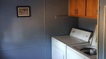 A laundry room with a washing machine and dryer, wooden cabinets, and a small framed picture on the wall.
