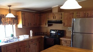 A kitchen with wooden cabinets, a stainless steel refrigerator, a stove, and a sink. - The West Bay Lodge offers spacious amenities for a perfect getaway.  (Cedar Island)