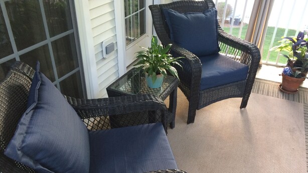 A covered patio area with wicker furniture, including a sofa and a chair, and a small table with a potted plant. - Gated Community: Top Corner Unit, Screened Porch Facing Woods, Beautiful Pool (Rehoboth Beach)