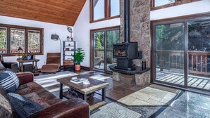 A spacious living room with a stone fireplace, large windows, and a cozy seating area.