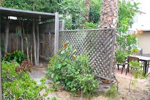 Enjoy al fresco dining or relaxation in this serene outdoor space surrounded by lush greenery and a wooden fence.