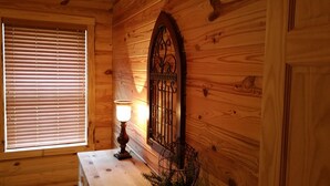 A wooden interior with a window with blinds, a table with a lamp, and a decorative iron gate. - Beautiful cabin style home backing up on the White River! (Mountain View)