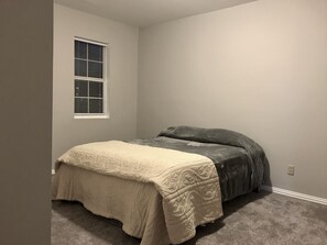 Une chambre à coucher avec un lit, une fenêtre et un sol recouvert de moquette.