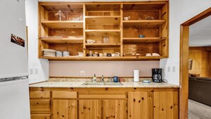 Une cuisine avec des meubles de rangement en bois, un plan de travail en marbre et une étagère intégrée.