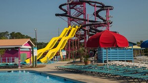 A water park with a large yellow slide, a red water tower, and a pool area with lounge chairs. - Audrey House, Pet Friendly, Blocks from Beach (NORTH MYRTLE BEACH)