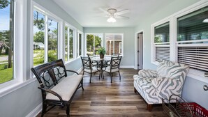 A dining area with a table and chairs, a ceiling fan, and large windows. - Audrey House, Pet Friendly, Blocks from Beach (NORTH MYRTLE BEACH)