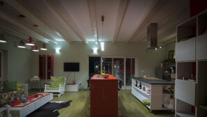 Ein geräumiges Wohnzimmer mit einer zentralen Insel, einer Couch und einem Essbereich, mit einer Küche im Hintergrund.