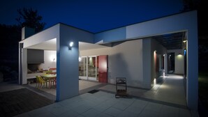 Ein modernes Haus mit offener Küche und Essbereich, einer überdachten Terrasse und einem gut beleuchteten Innenraum.