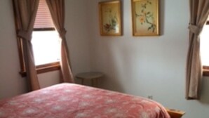 Ein Schlafzimmer mit einem großen Bett, zwei gerahmten Bildern an der Wand und einer Klimaanlage.