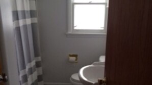 Ein Badezimmer mit Toilette, Duschvorhang und Fenster.