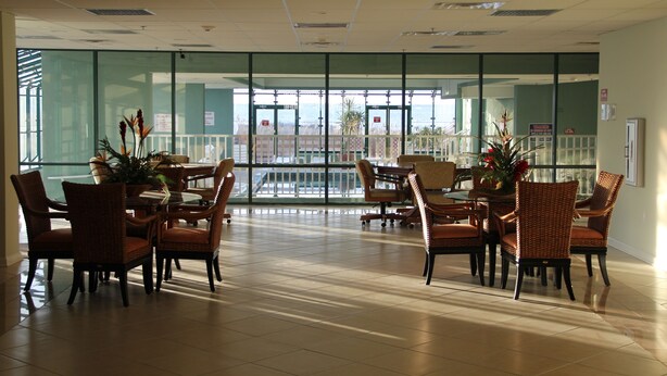 A spacious dining area with glass walls, modern furniture, and a view of the cityscape. - Magnificent Bay View!!! Luxurious Condo, Your Home-Away-From-Home, Makai #316 (Ocean City)