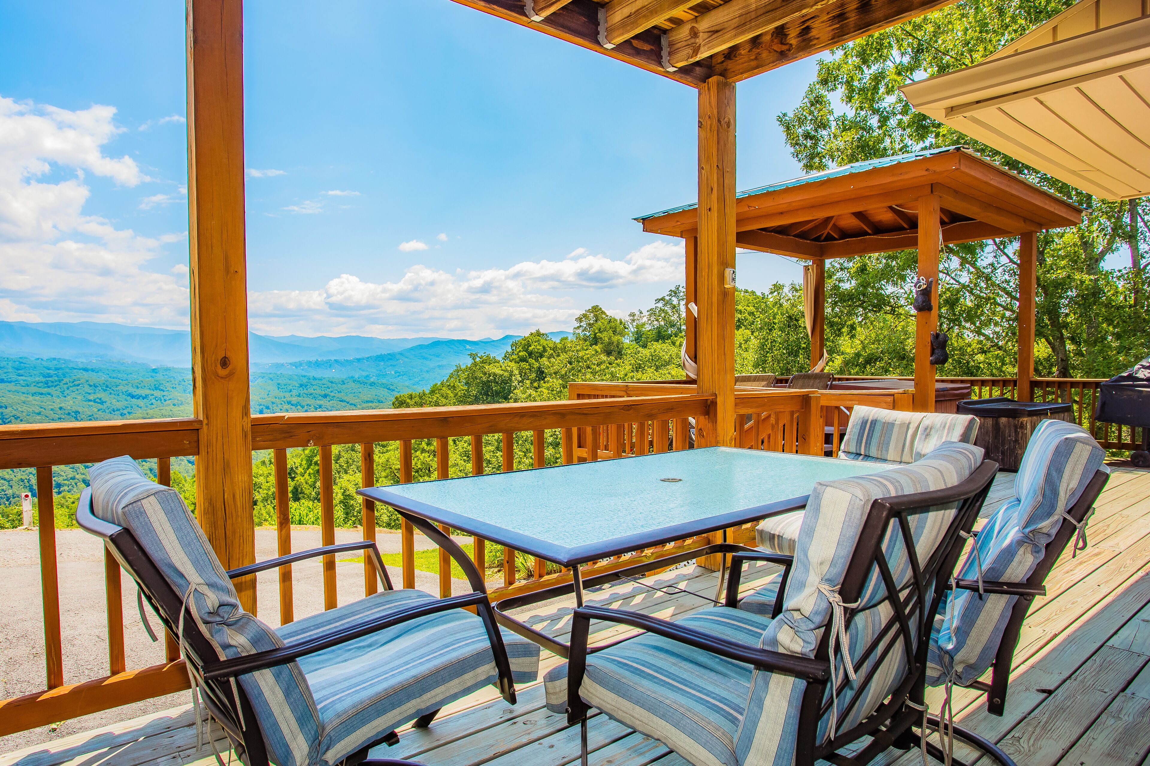 Une terrasse en bois avec une table et des chaises, offrant une vue sur un paysage montagneux.