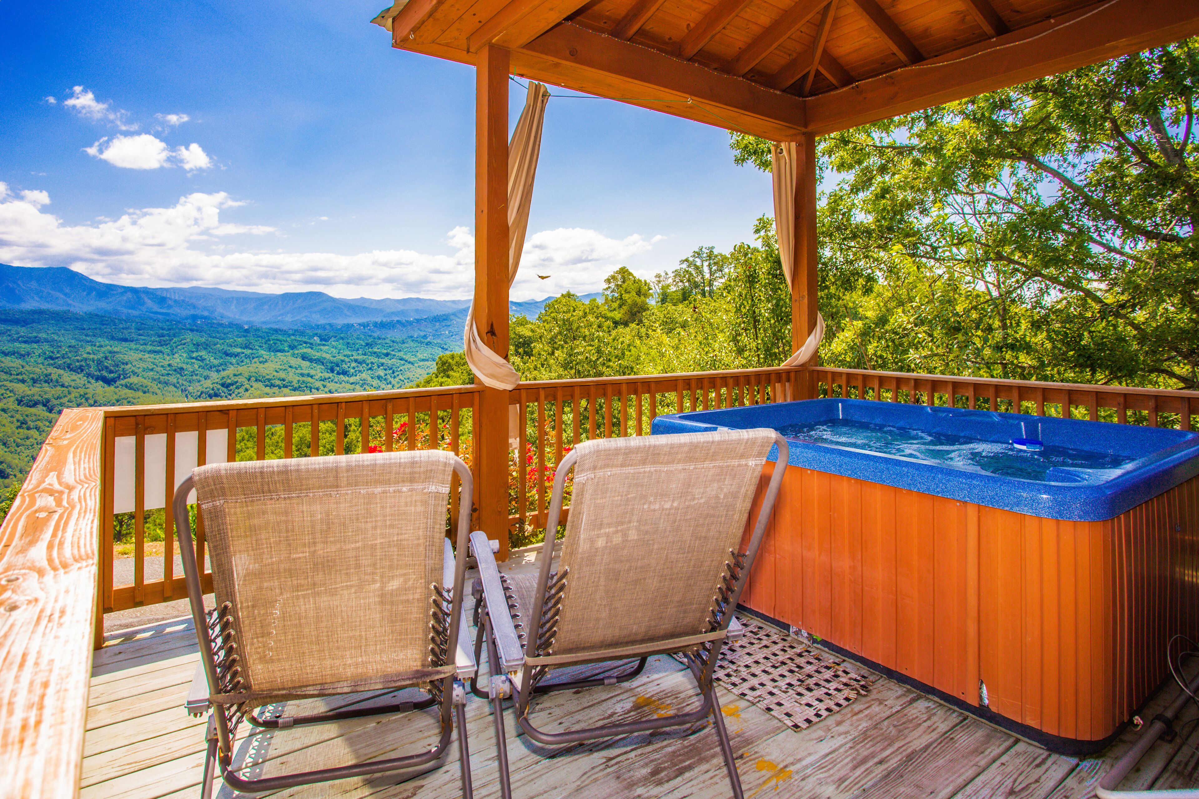 A wooden deck with two wicker chairs and a hot tub.