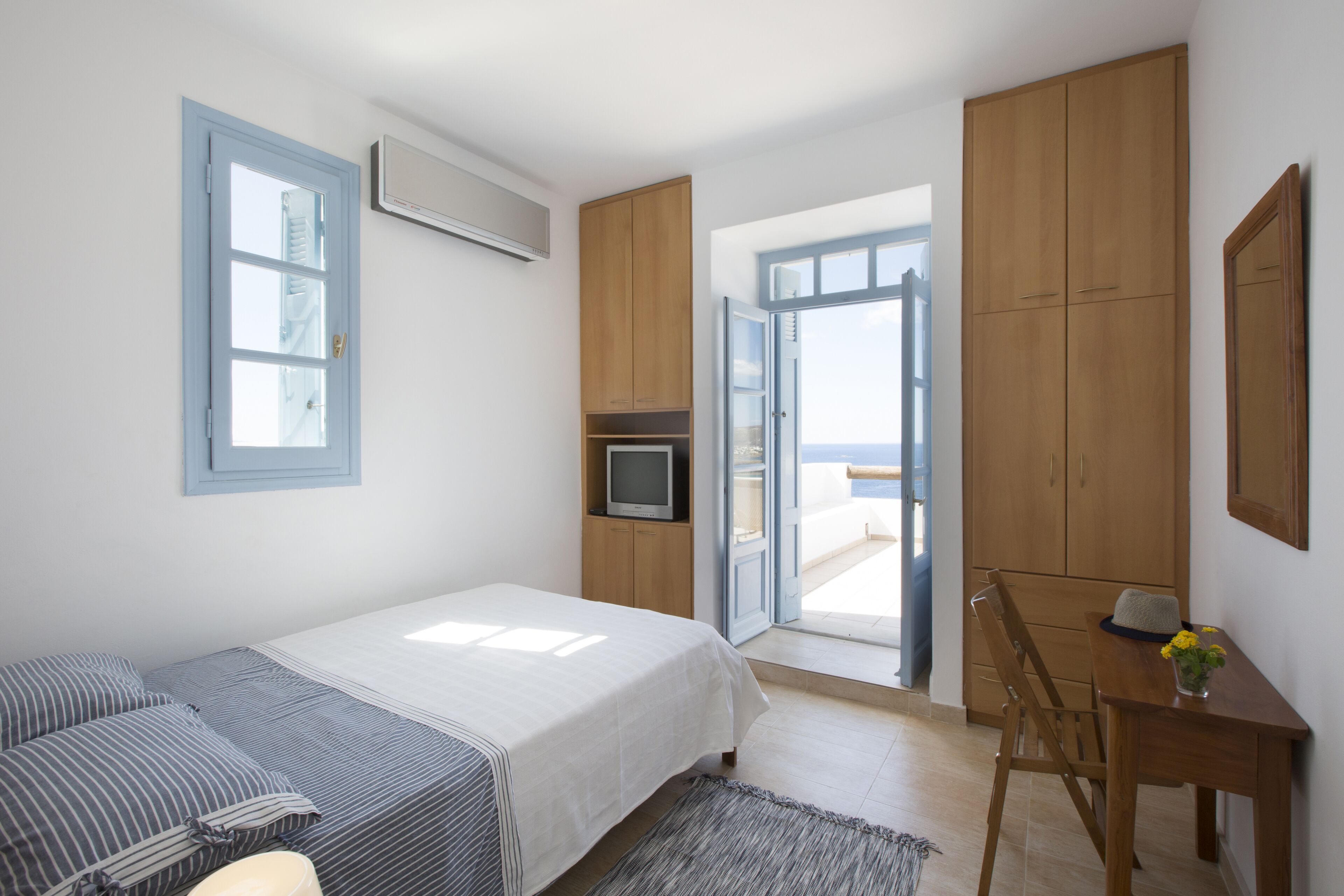 A bedroom with a bed, a desk, and a television.