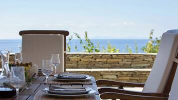 A wooden table set for dining with a view of the sea.