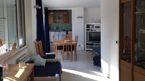 A compact living space with a kitchenette, a dining area, and a seating area with a sofa and a desk. - Villa Asia, Holiday home (Massa Lubrense)