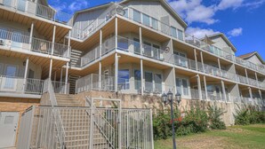 A multi-story hotel with balconies, a gated entrance, and a clear sky. - Riviera | Pools & Hot-Tubs | Pet-Friendly* | King Bed (New Braunfels)