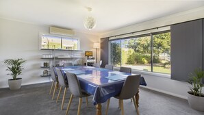 A modern conference room with a large table, chairs, and a view of greenery outside.