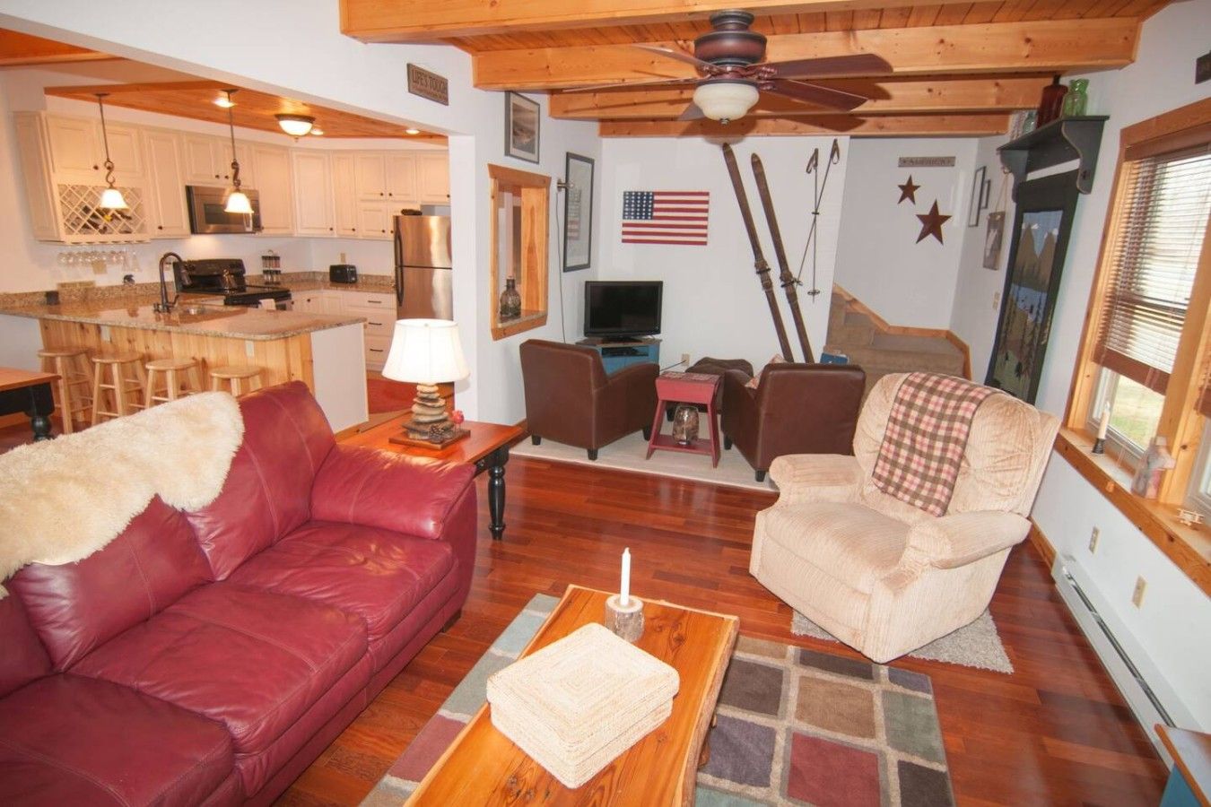 A living room with a red leather sofa, a beige armchair, a coffee table, and a television.