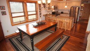 A kitchen with wooden cabinets, a central island, bar stools, and a stainless steel refrigerator. - Three Bears in the Valley - Hot Tub, Pet Friendly (Davis)
