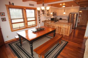 Una cucina con mobili in legno, un'isola centrale, sgabelli da bar e un frigorifero in acciaio inossidabile.