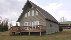 A two-story house with a wooden deck and a large window on the second floor. - Three Bears in the Valley (Davis)