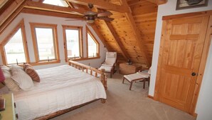 A bedroom with a sloped ceiling, a bed, a chair, a desk, and a wardrobe. - Three Bears in the Valley - Hot Tub, Pet Friendly (Davis)