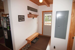 A hallway with a wooden bench, a door, and a wall-mounted sign.