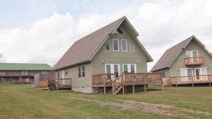 A two-story building with a sloped roof, wooden decks, and a green exterior. - Three Bears in the Valley - Hot Tub, Pet Friendly (Davis)