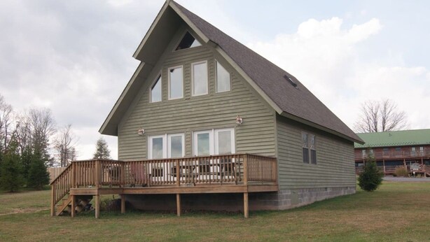 A single-story house with a wooden deck and a green roof. - Three Bears in the Valley - Hot Tub, Pet Friendly (Davis)