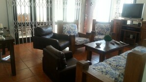 Uma sala de estar com sofá, poltronas, mesa de centro e televisão.