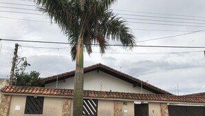 Um edifício residencial com telhado de cerâmica, uma palmeira e um carro preto estacionado.