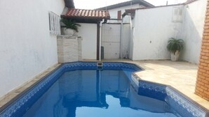 Uma piscina retangular com borda azulejada e uma pequena abertura retangular no centro.