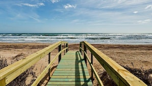 Ein hölzerner Steg führt zum Strand.
