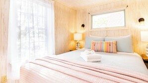 A hotel room with a bed, a window, and a nightstand with a lamp. - Waterfront Views of Creek- Beach Access! (Wellfleet)