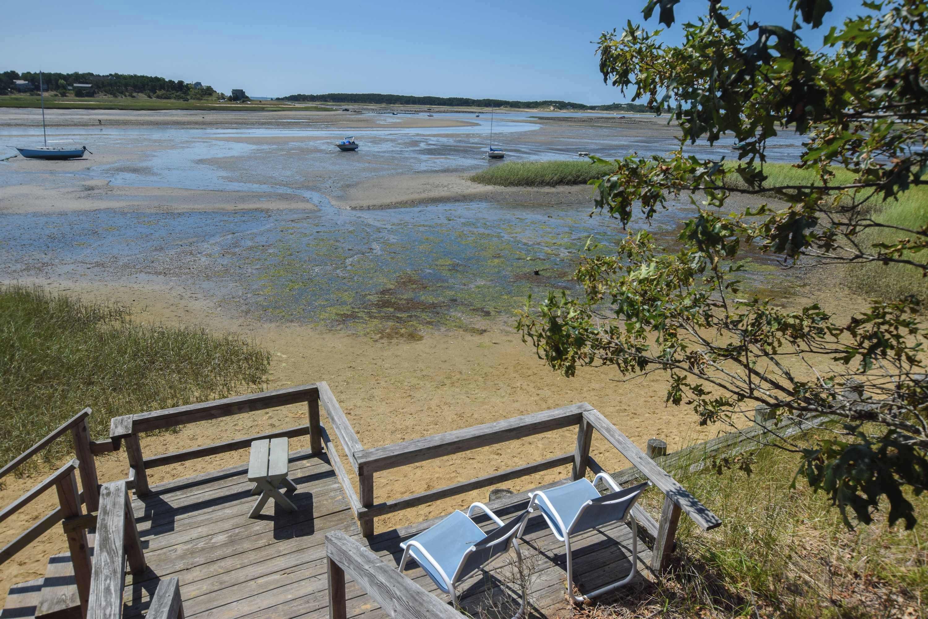 A wooden deck with benches overlooking a beach with boats.