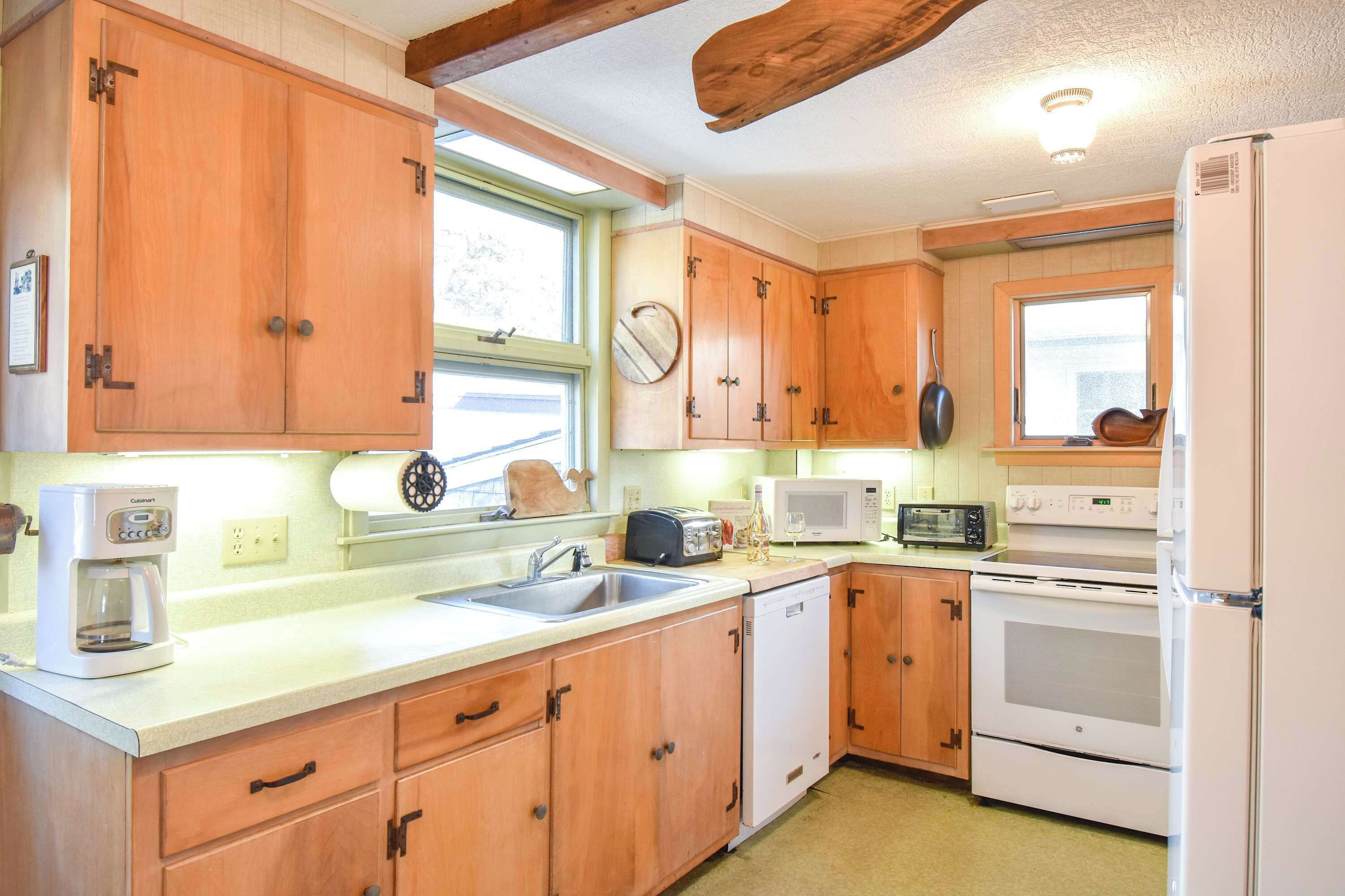 A kitchen with wooden cabinets, a sink, a coffee maker, a microwave, a toaster, and a stove.